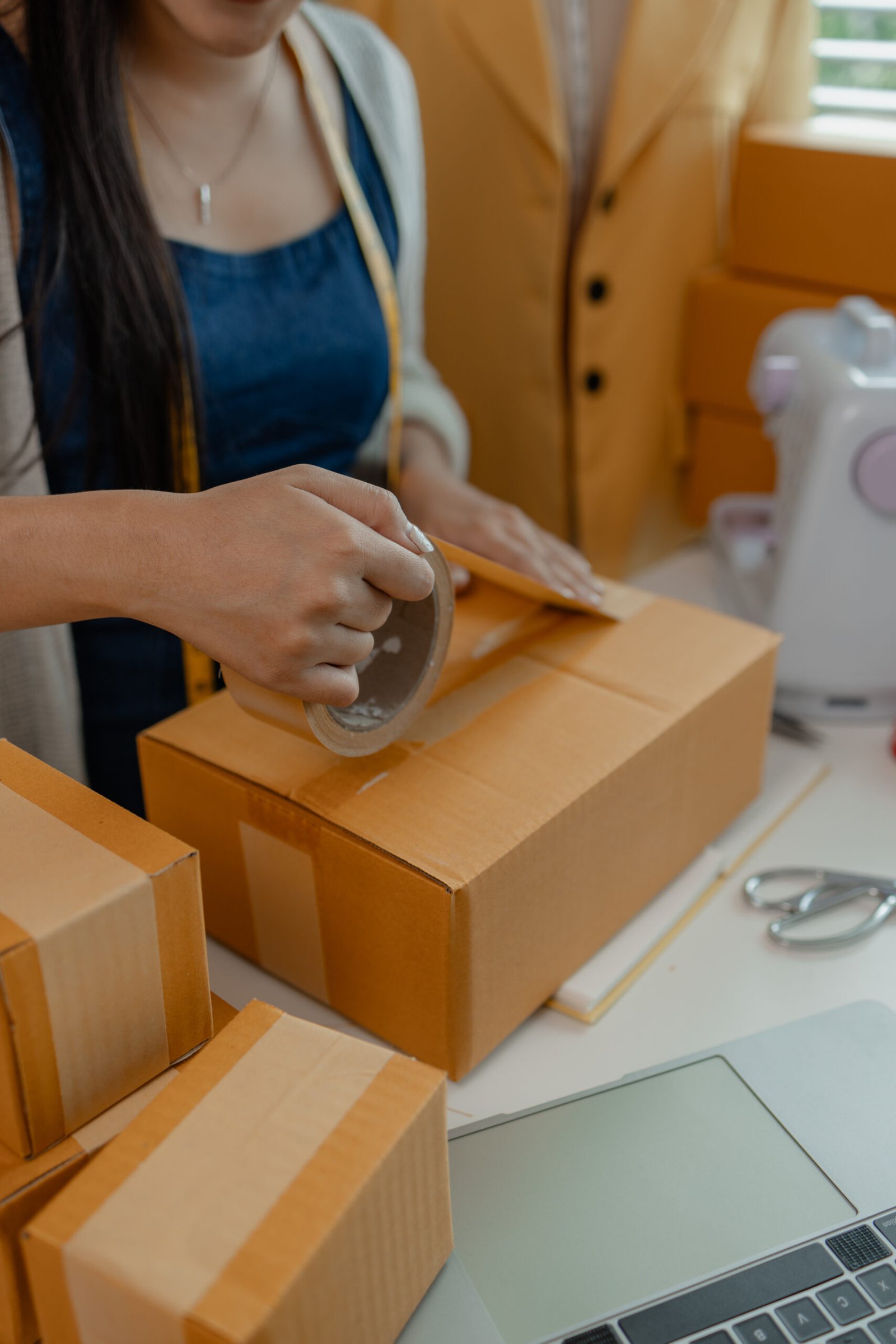 a designer is preparing products to send to customers by mail, a female dressmaker is selling her products online to increase her income, female industrial tailor at work
